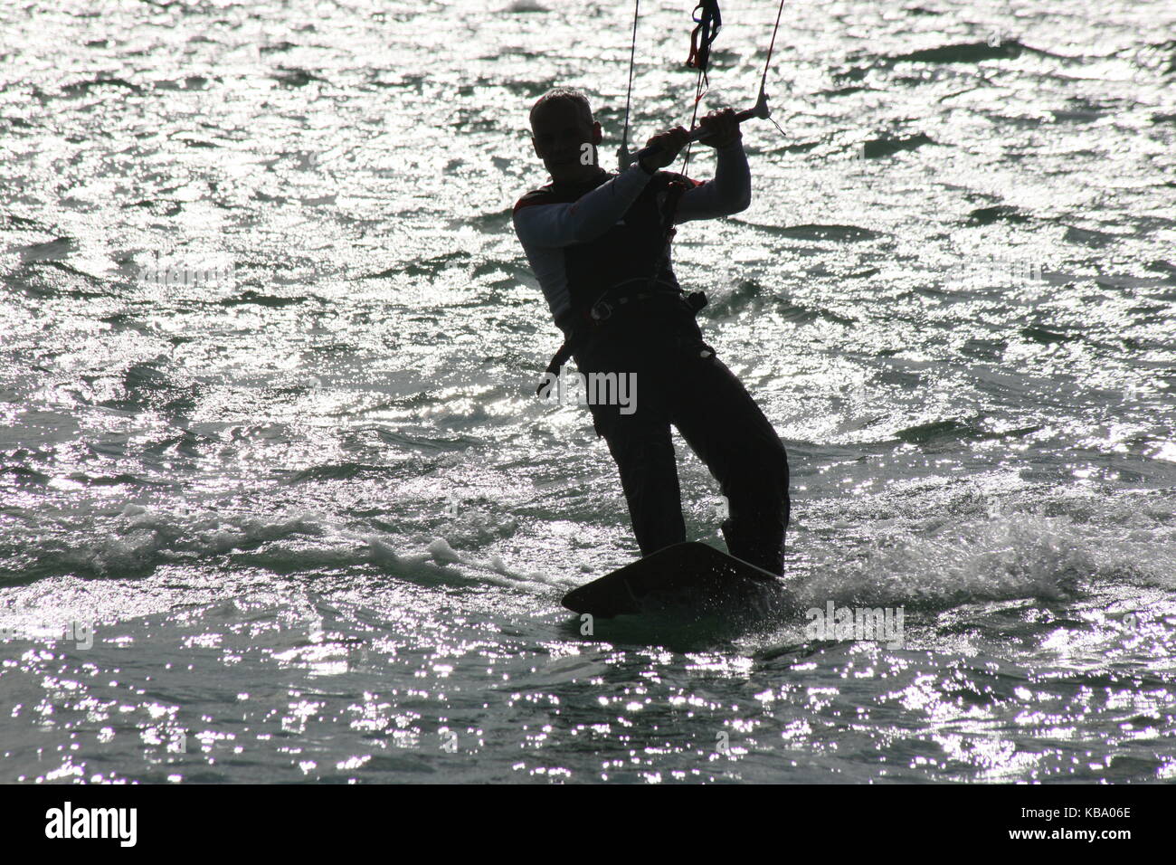 Surfer sulla tavola da surf con vela --- Kite Surfer auf Surfboard im Gegenlicht Foto Stock