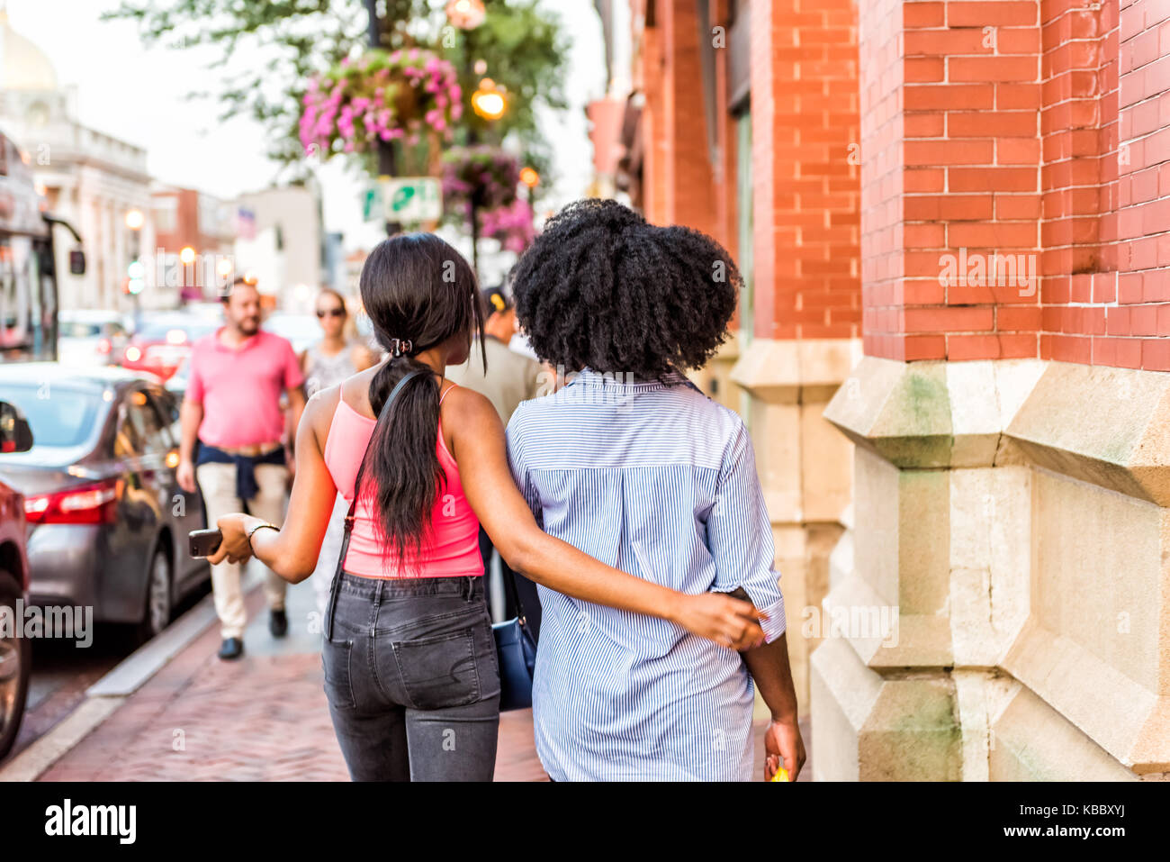 Washington DC, Stati Uniti d'America - 4 Agosto 2017: due amiche amici ragazze persone che camminano in sera abbracciando, le braccia intorno al corpo nel centro cittadino di Georgetown neighb Foto Stock