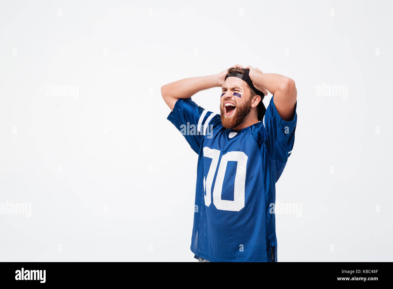 Triste urlando emotional man ventola in blu t-shirt in piedi isolato su sfondo bianco. Guardando a parte. Foto Stock