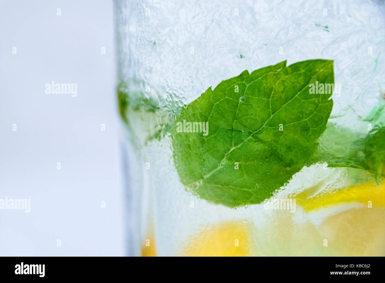 Angolazione laterale vista del mojito fresco in vetro con foglie di menta verde di cubetti di ghiaccio e le fette di limone Foto Stock