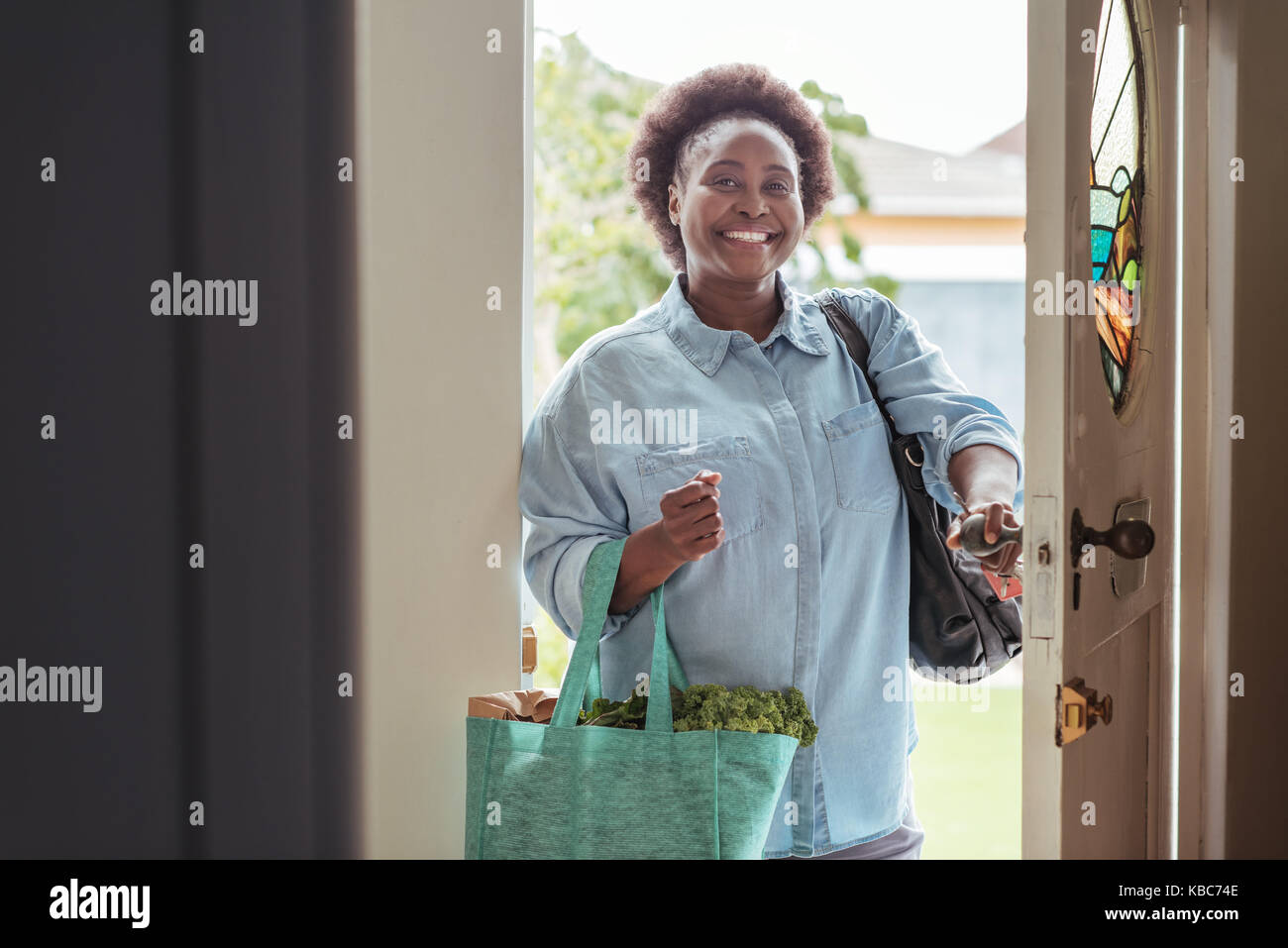 Sorridente donna africana che arrivano a casa dal supermercato Foto Stock