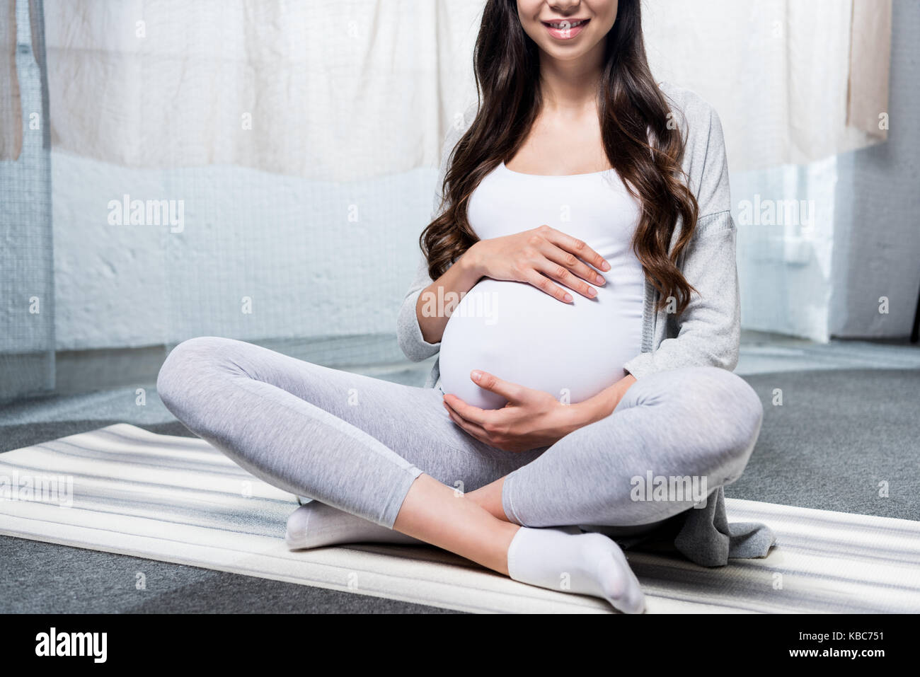 Donna incinta seduta in lotus pongono Foto Stock
