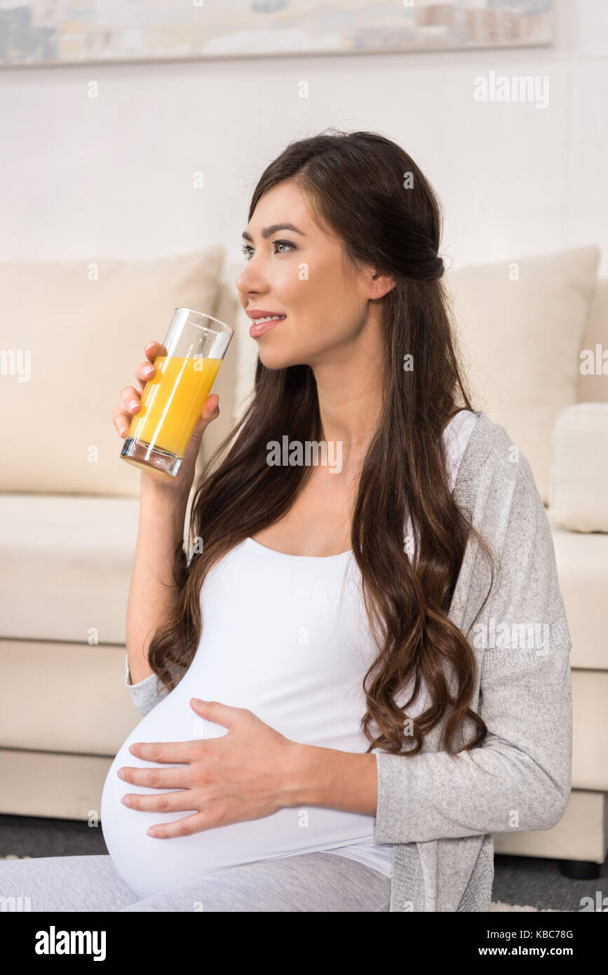 Donna incinta di bere un bicchiere di succo di frutta Foto Stock