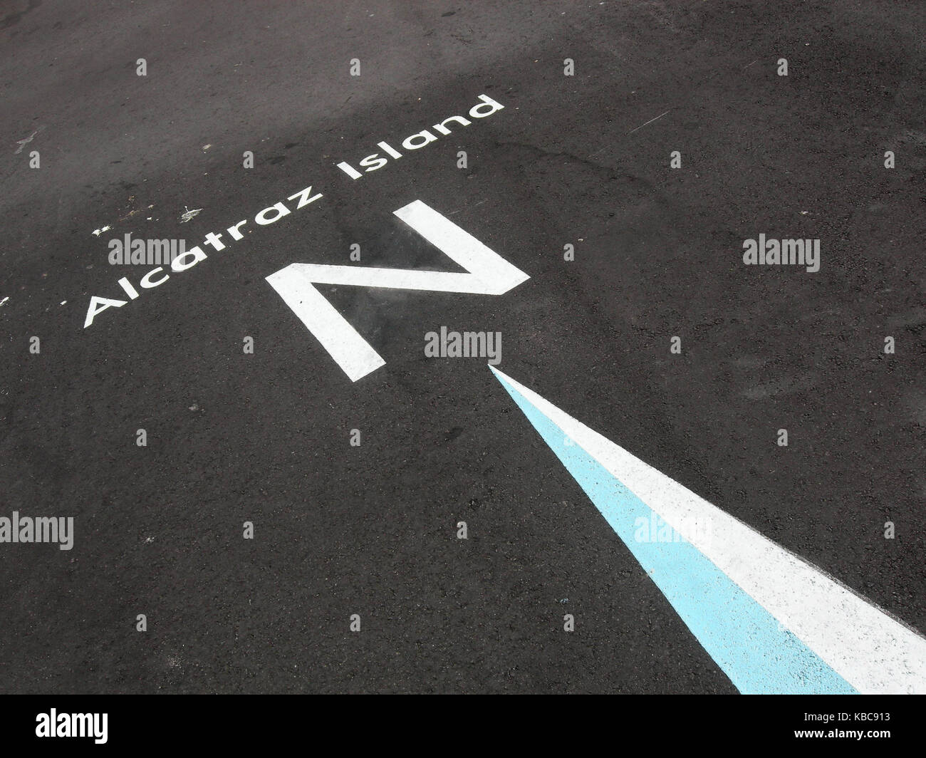 Bianco freccia della bussola sul grigio asfalto terra rivolta verso nord in direzione di Alcatraz a San Francisco, Stati Uniti d'America. Foto Stock