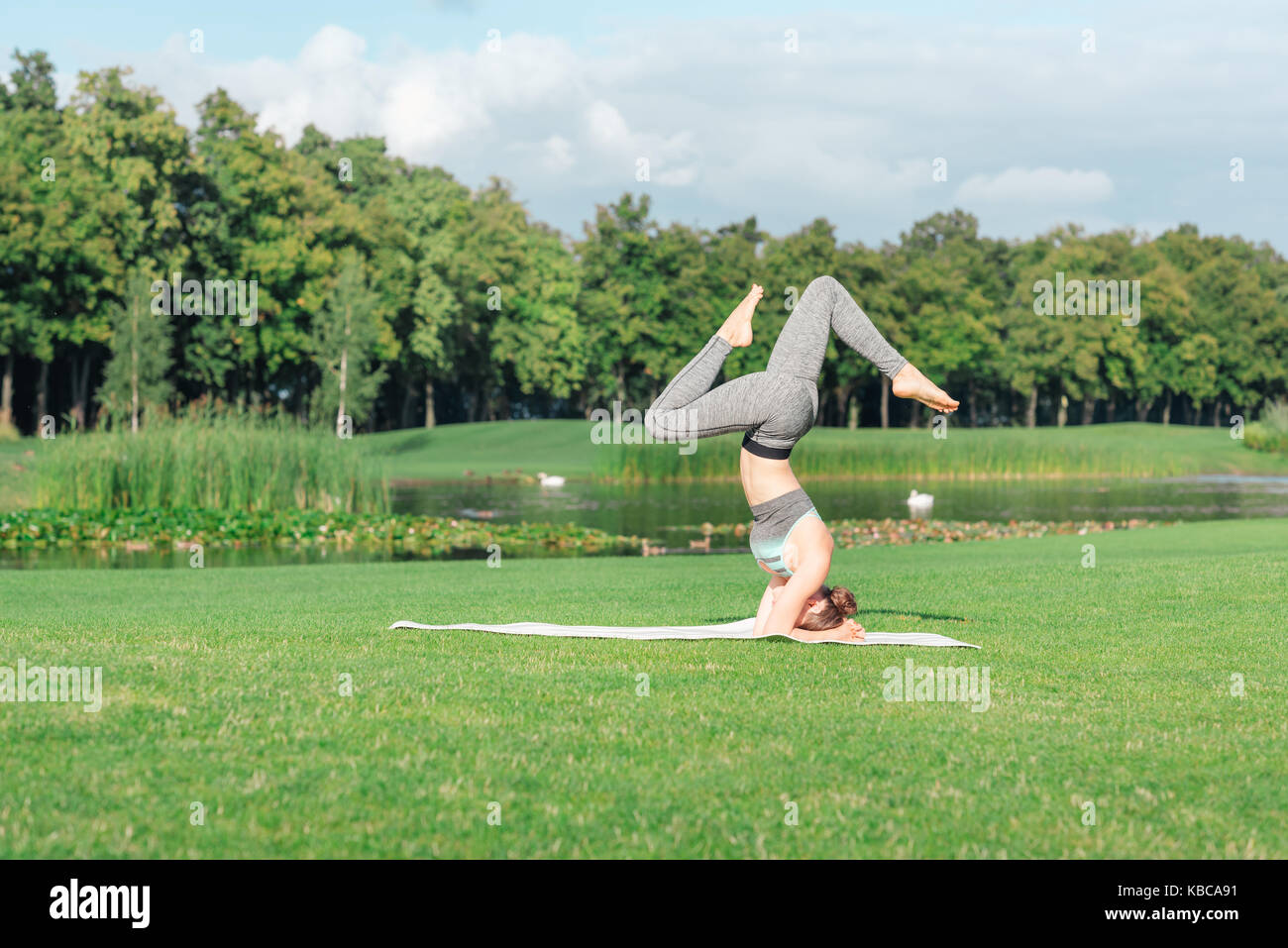 Donna di eseguire lo yoga headstand pongono Foto Stock