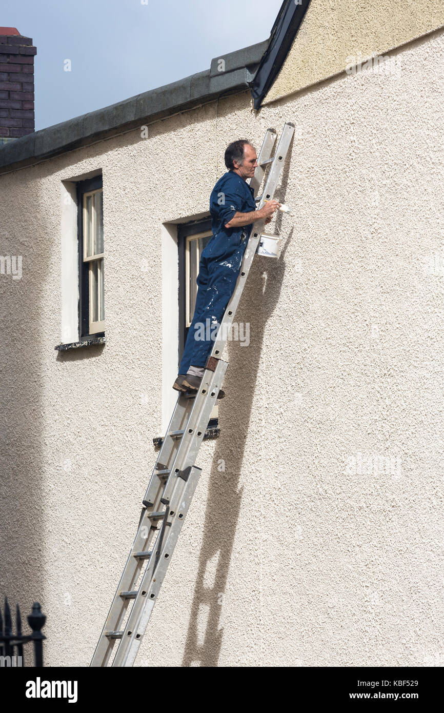 L uomo sulla scala di pittura parete esterna di una casa al di fuori Foto Stock