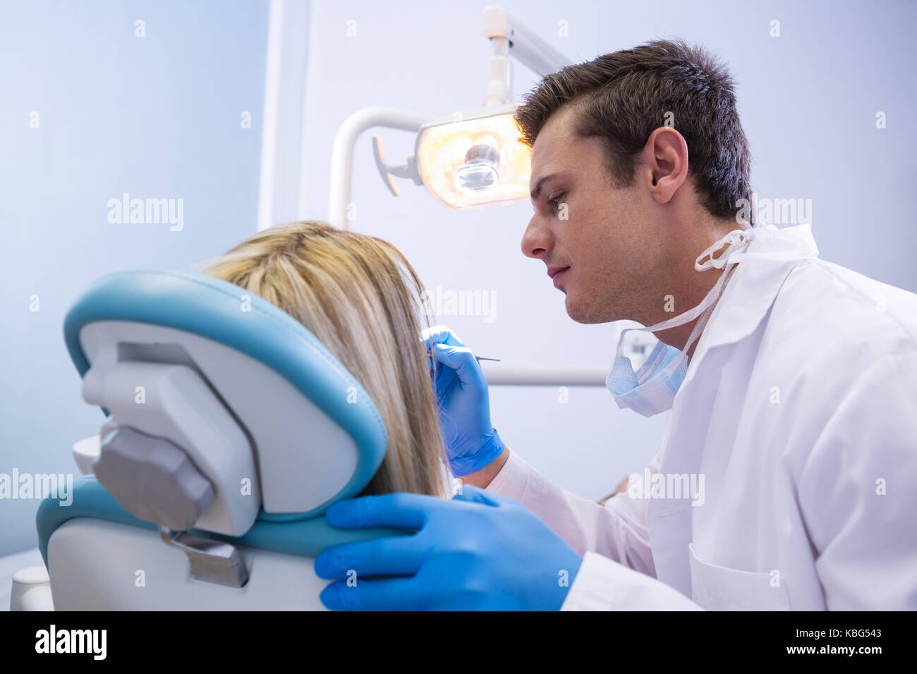 Vista laterale del dentista donna di lucidatura dei denti clinica dentale Foto Stock