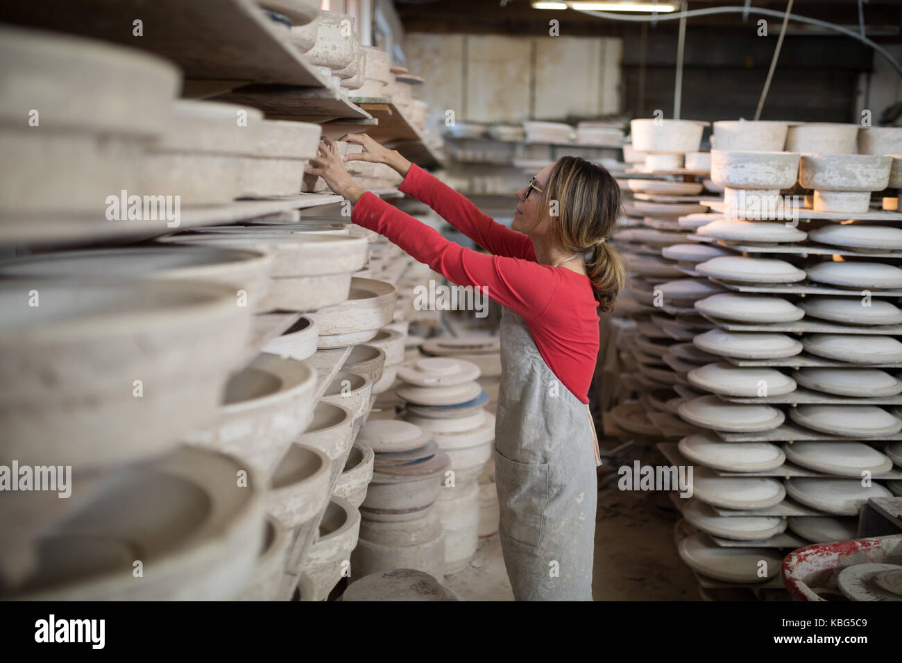 Potter femmina immissione prodotto artigianale nel ripiano nel laboratorio di ceramica Foto Stock