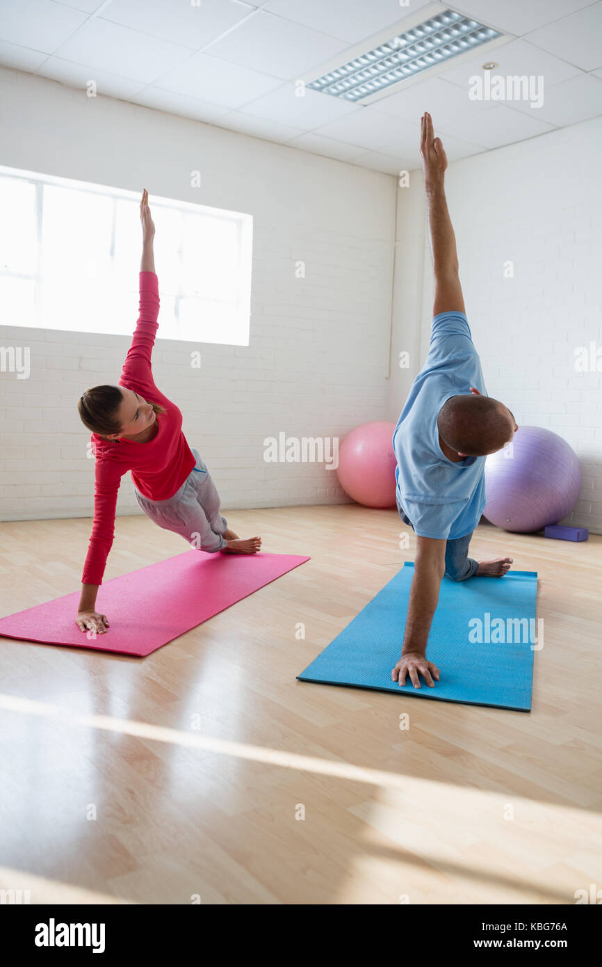 Istruttore Yoga con gli studenti praticanti listone laterale pongono nel club salute Foto Stock