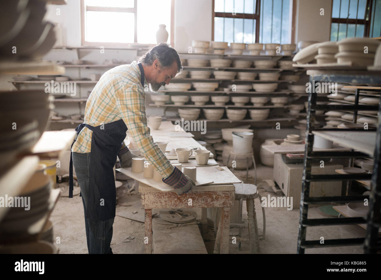 Potter maschio lavora al piano di lavoro nel laboratorio di ceramica Foto Stock