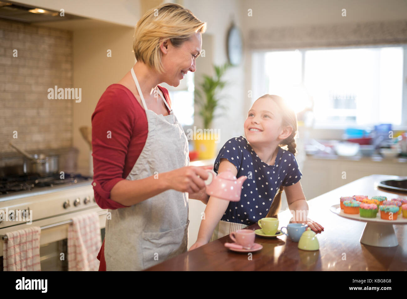 Madre e figlia versando il tè in tazze in cucina Foto Stock