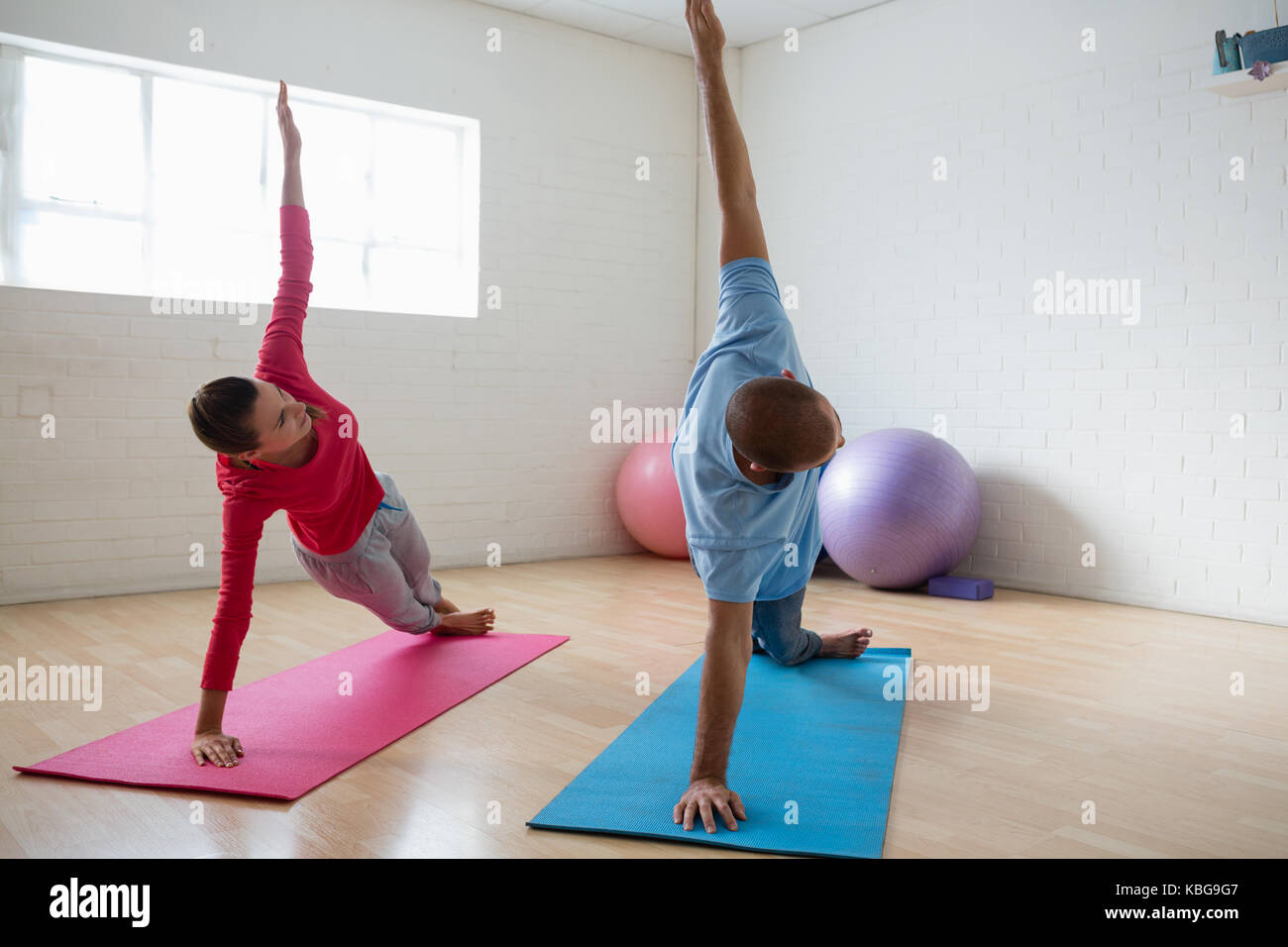 Istruttore maschio con femmina studente pratica posizione del cobra pongono in studio di yoga Foto Stock