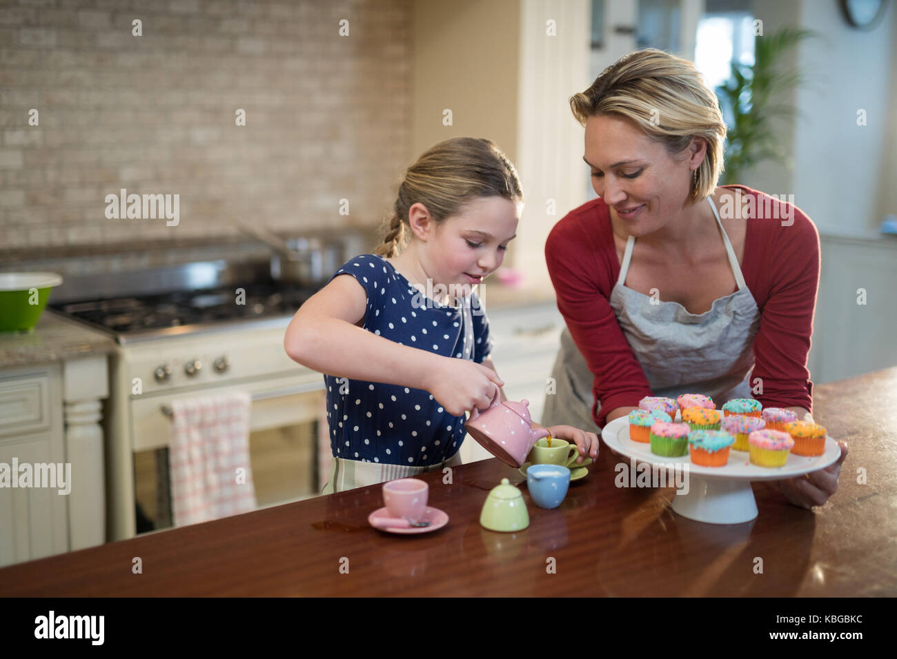 Madre e figlia versando il tè in tazze in cucina Foto Stock