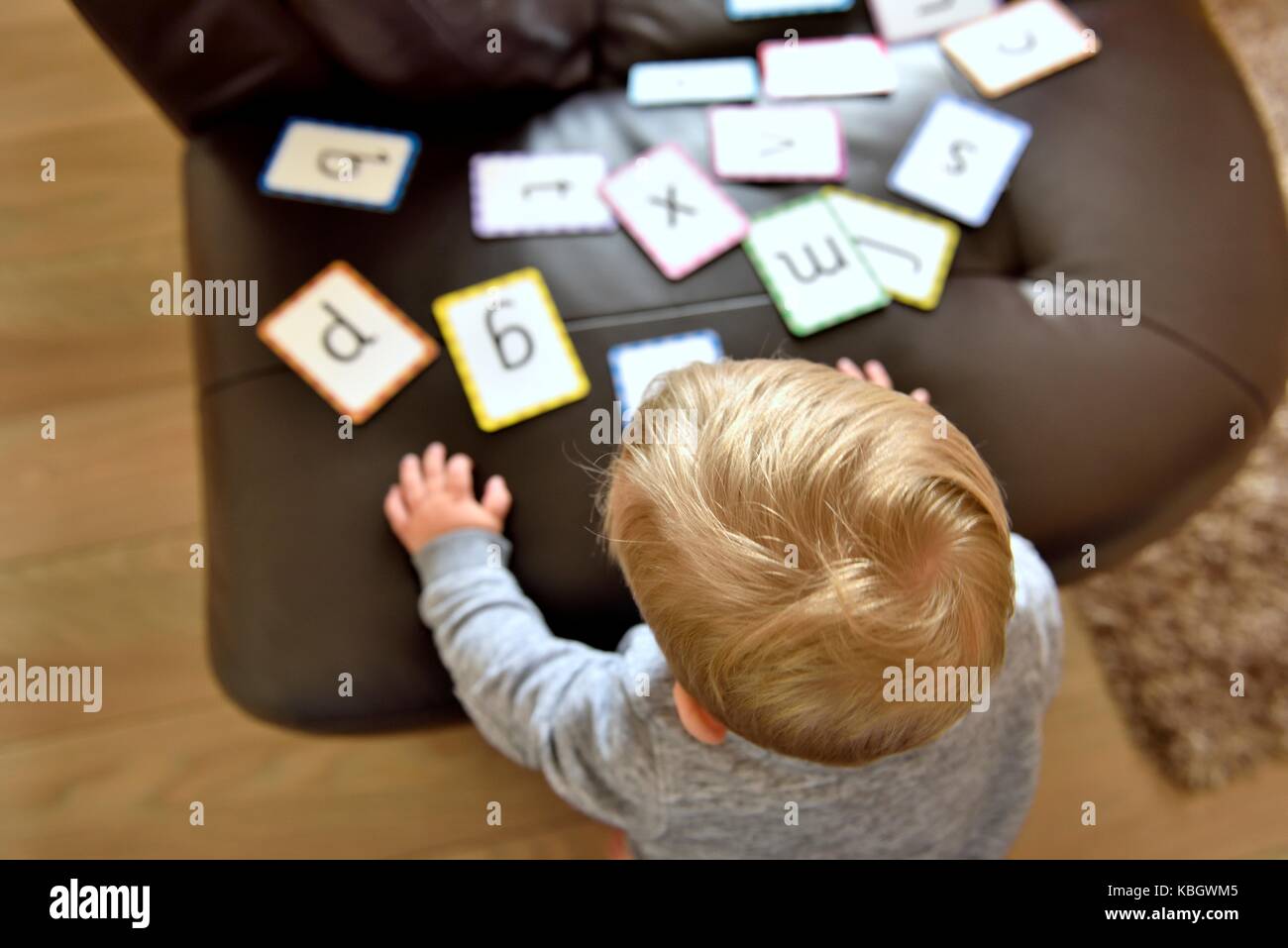Un giovane ragazzo toddler suonare con alcuni alfabeto schede di apprendimento Foto Stock