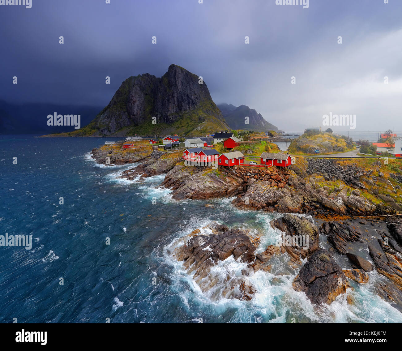 Pesca norvegese village reine sulle isole Lofoten. rosso rorbu norvegese case sul litorale di pietra. natura nordica al maltempo. blu delle onde del mare Foto Stock