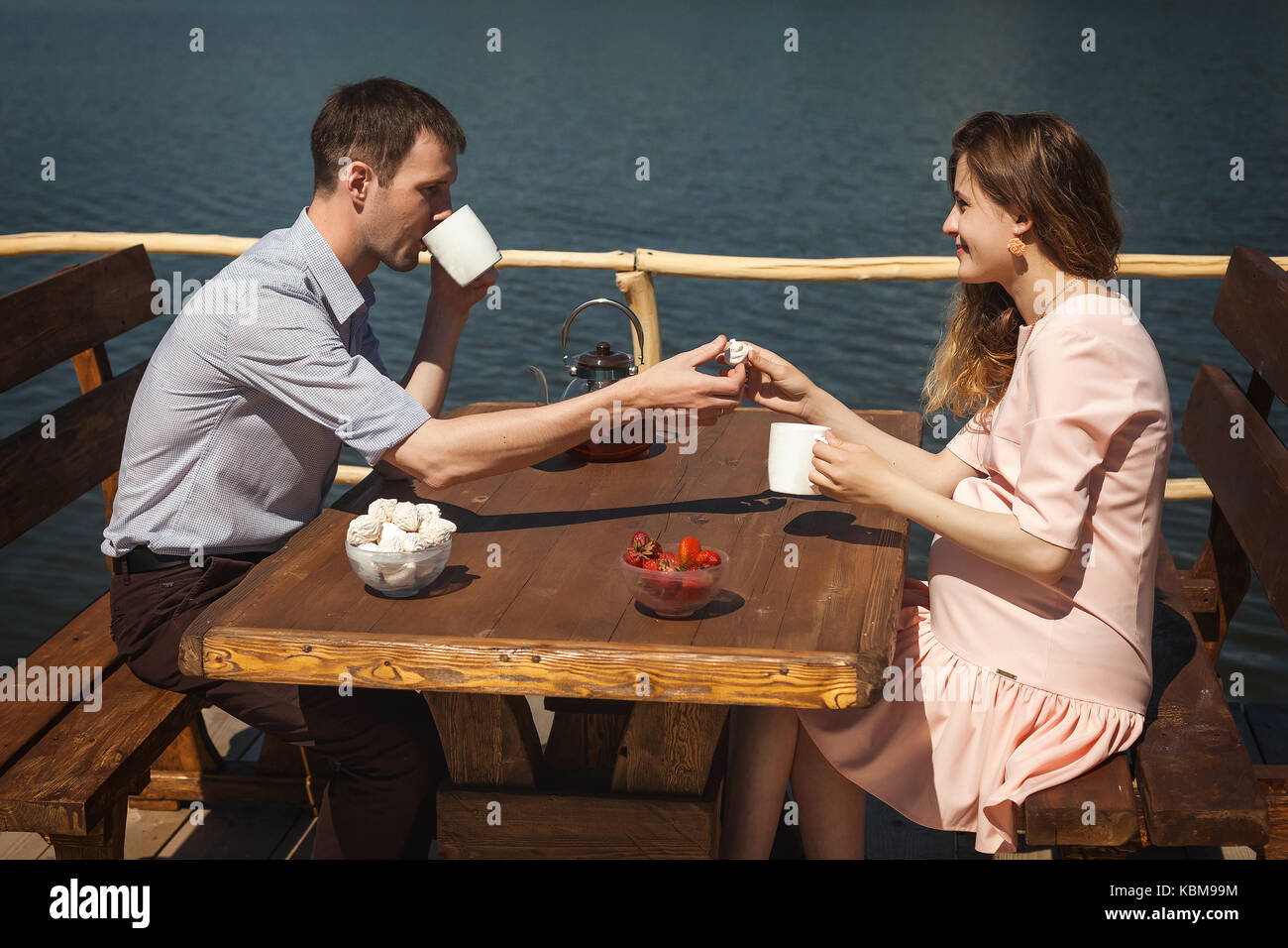 Felice coppia giovane bere il tè all'aperto, gli amanti della bella l uomo e la donna hanno un buon tempo sul molo con una tazza di tè Foto Stock