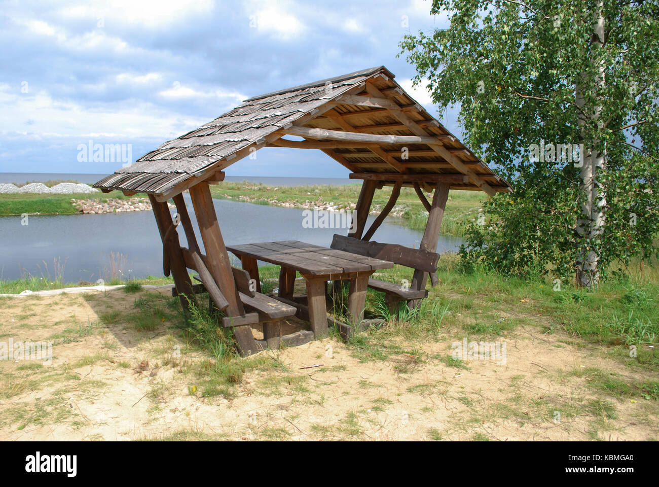 Attrezzata area pic-nic (panchine di legno e tettoia) sulla riva del lago. Foto Stock