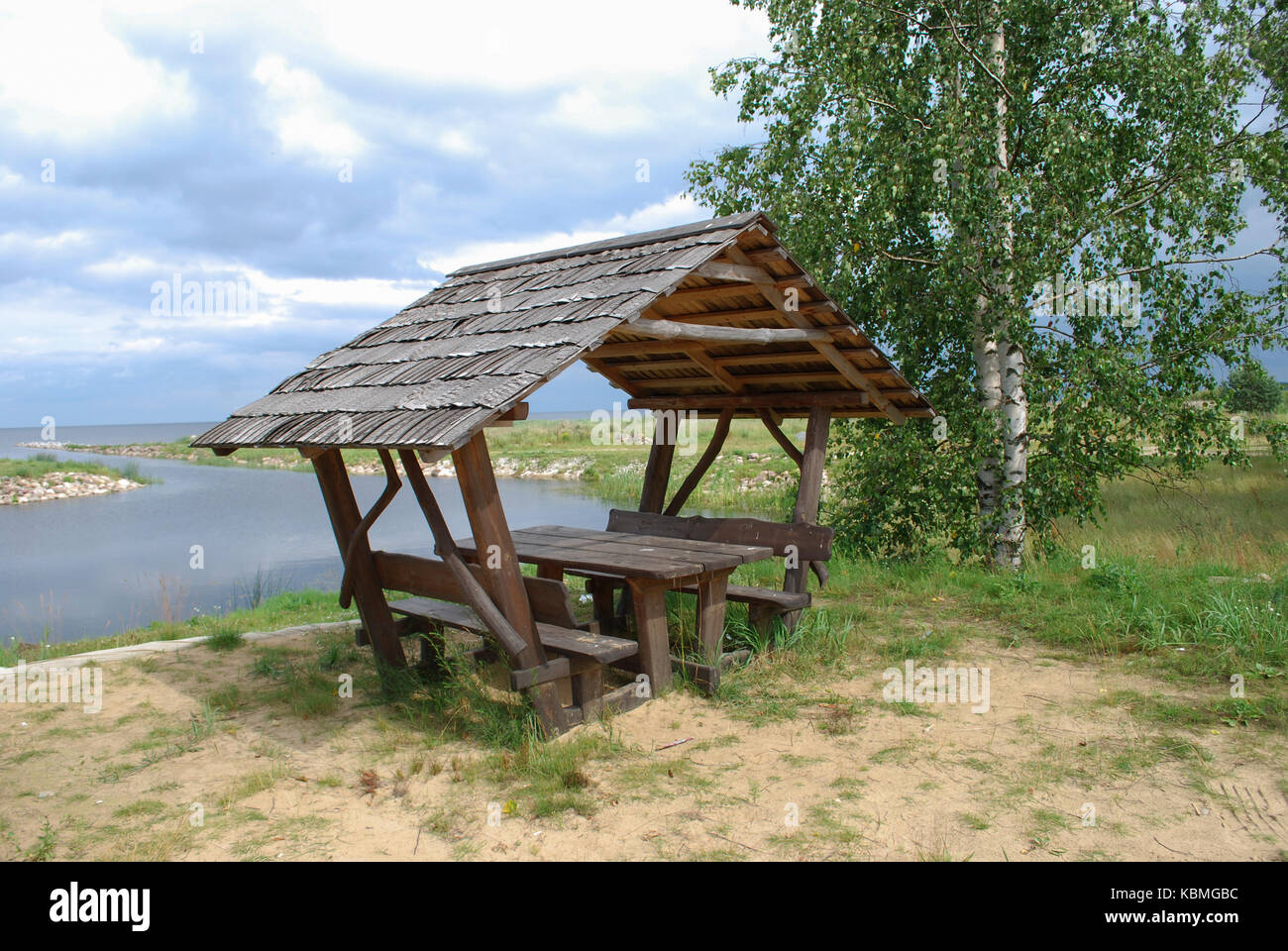 Attrezzata area pic-nic (panchine di legno e tettoia) sulla riva del lago. Foto Stock
