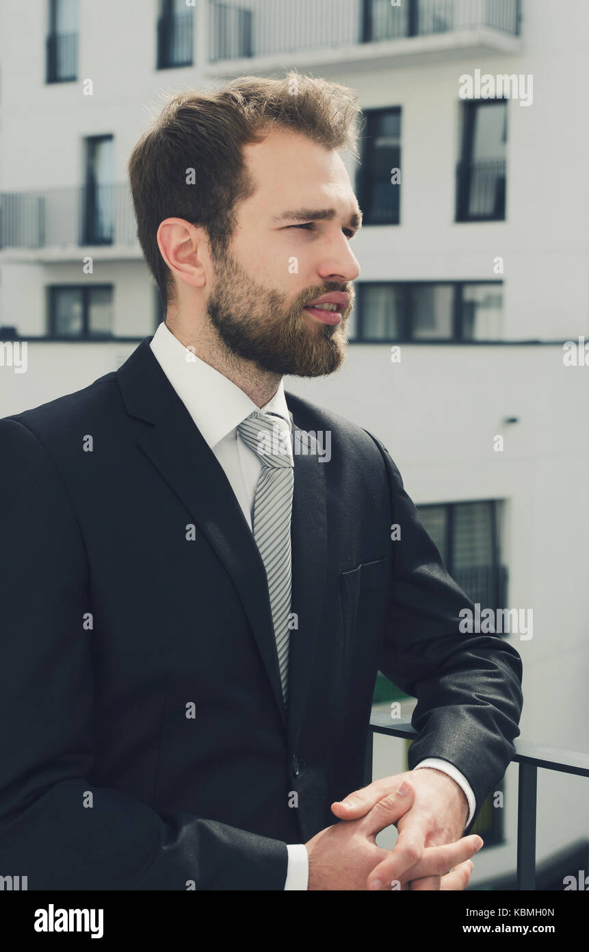 Imprenditore rilassato in piedi sul balcone del suo appartamento. imprenditore outdoor friendly tuta caucasica balcone appartamento city concept Foto Stock