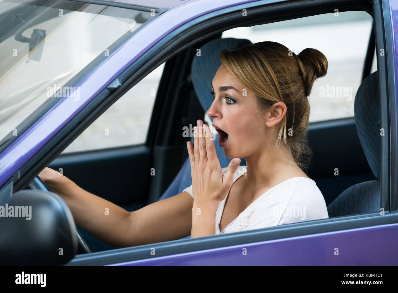 Scioccato giovane donna con la bocca aperta la guida auto Foto Stock