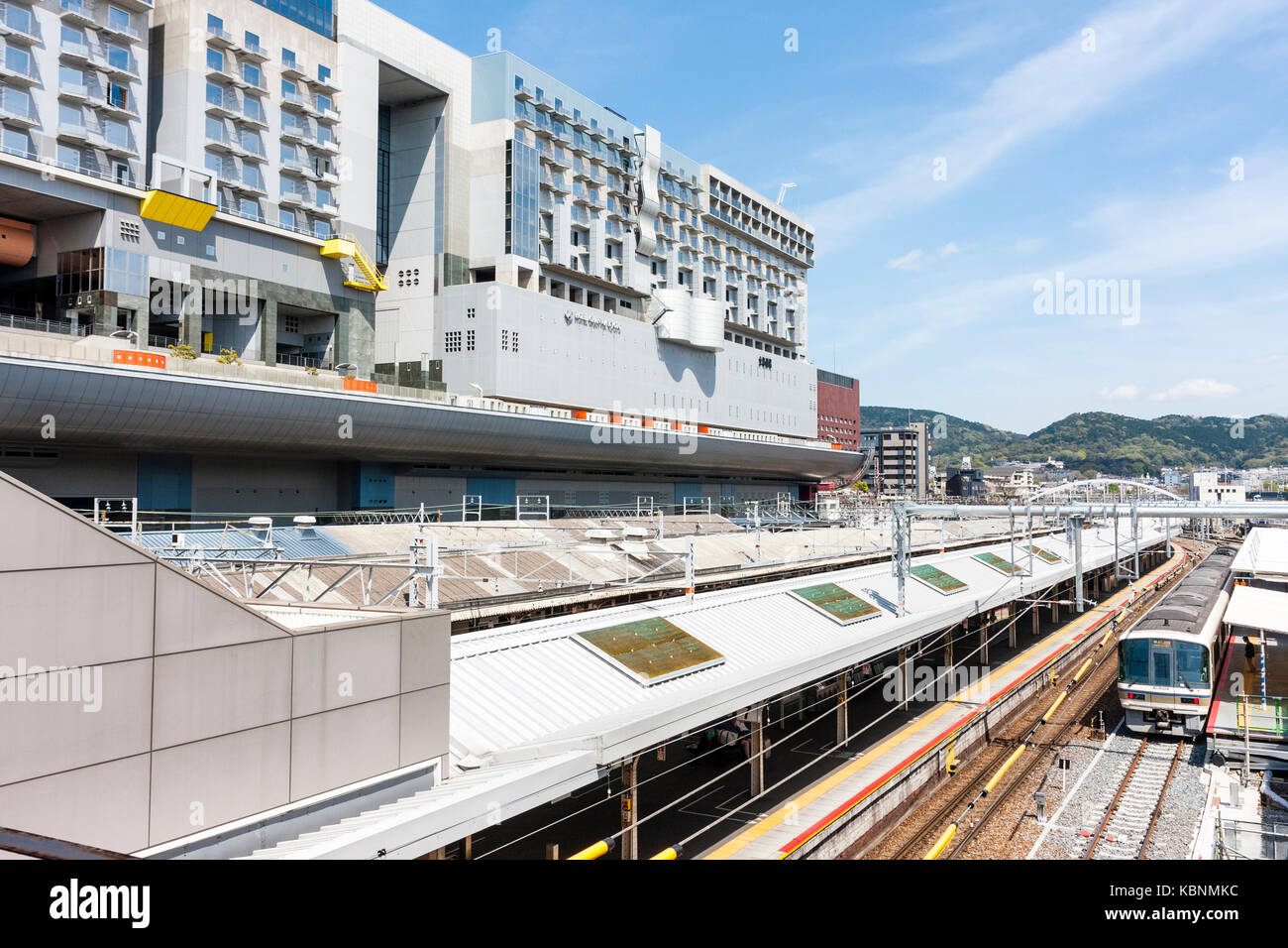 Kyoto stazione ferroviaria. Vista aerea, treno in attesa sul tetto coperto piattaforma, sulla sinistra l'edificio della stazione e Hotel Granvia. Sole e cielo blu. Foto Stock