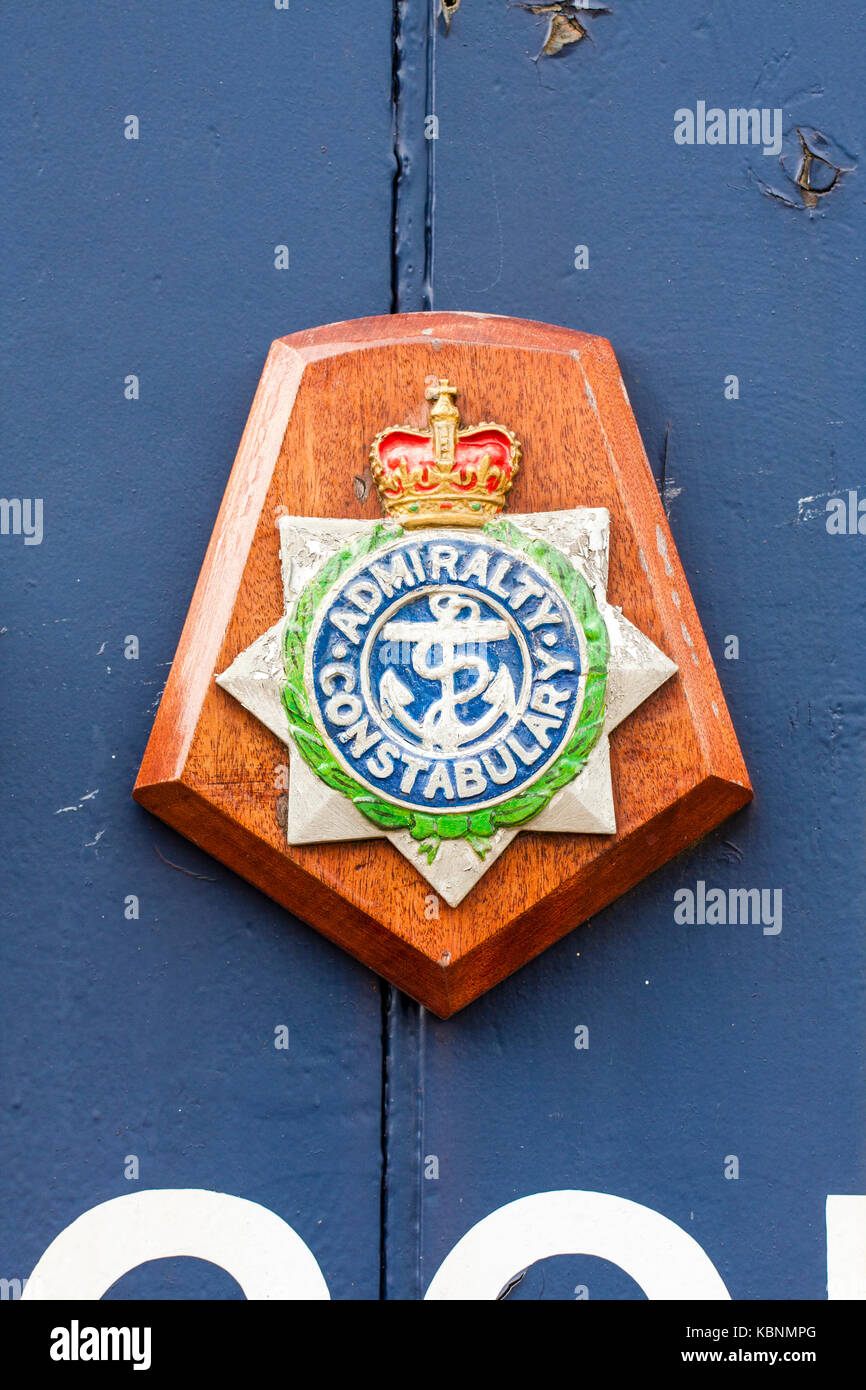 Inghilterra, Chatham. Il badge dell'ammiragliato constabulary nel blu dipinto di pannello in legno. Icona è la corda ed ancoraggio. La polizia militare. Foto Stock