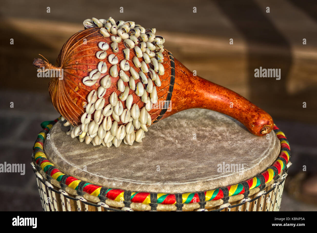 Tamburo di Shekere del Ghana africano (strumento di percussione africano dal Ghana. Noto anche come Axatse) isolato con sfondo sfocato. Foto Stock