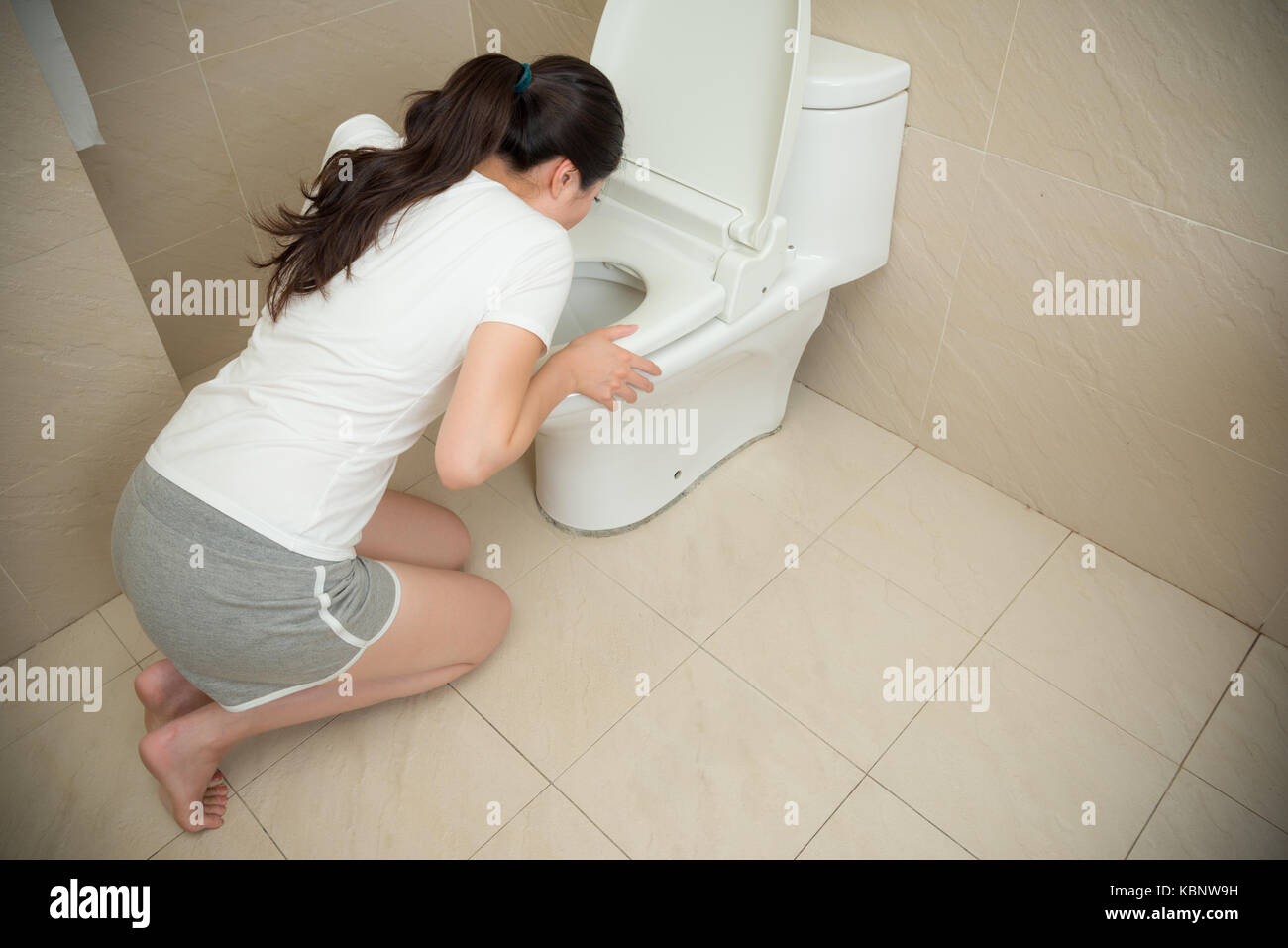 Angolo alto consente di visualizzare la foto del dolce bella donna inginocchiati davanti al wc vomito su bagno a casa durante la gravidanza il tempo. Foto Stock