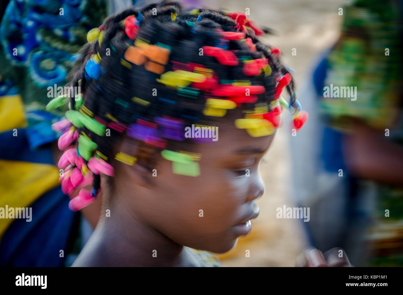 Giovane ragazza africana con splendidamente decorate capelli dancing, molto colorato con destinato motion blur, Cabinda Angola Foto Stock