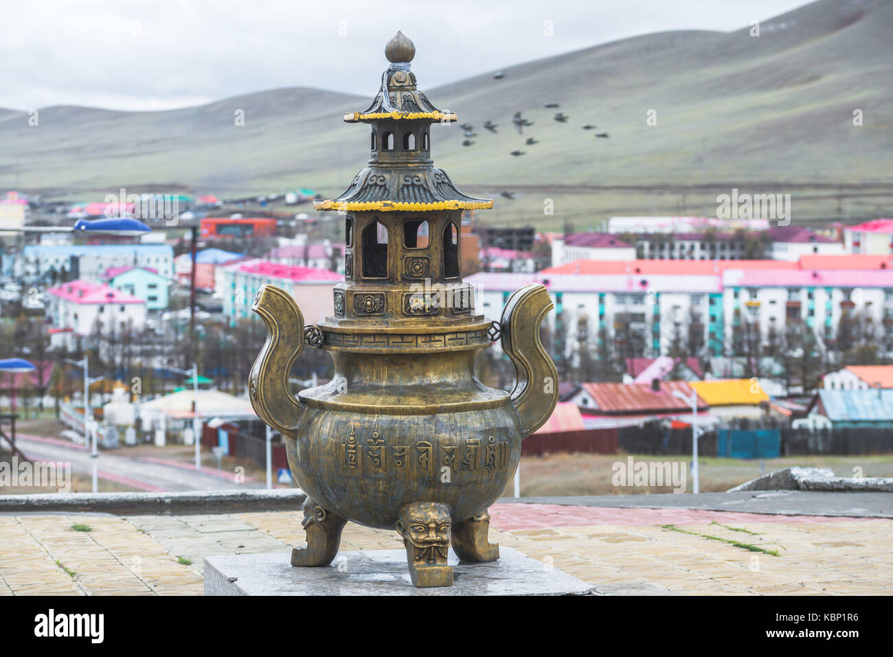 Metallo mongola statua religiosa sul piedistallo di granito con lunghi passi sullo sfondo Foto Stock