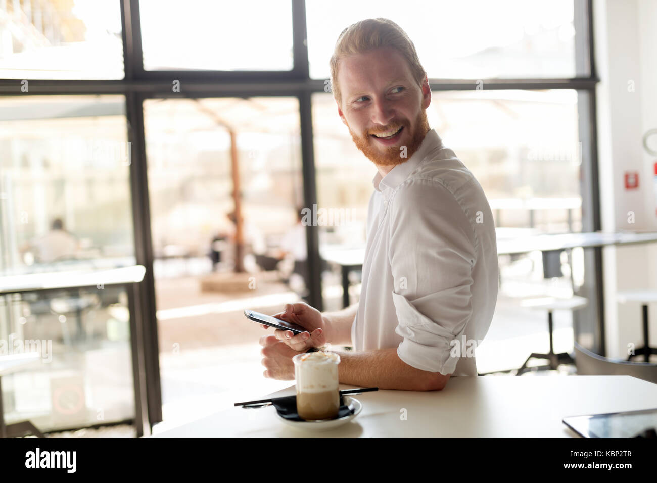 Imprenditore occupato bere un caffè mentre sono online Foto Stock