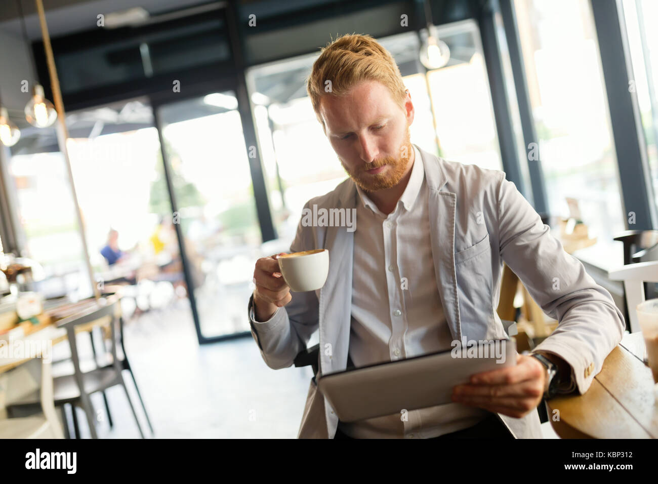 Imprenditore occupato bere un caffè mentre sono online Foto Stock
