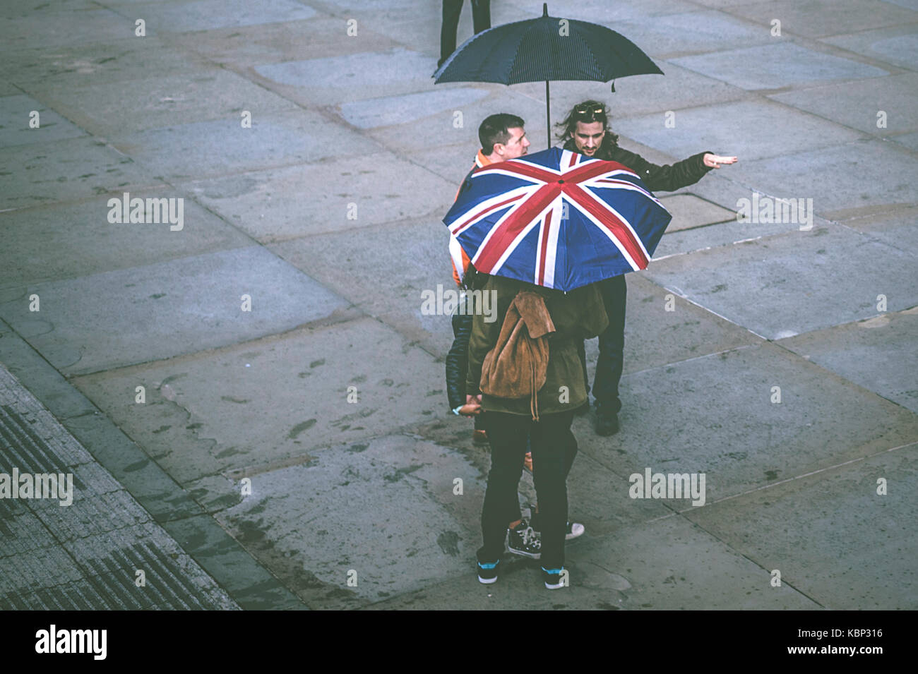 Gruppo di persone in possesso di un ombrello con i colori della union jack bandiera britannica. Foto Stock