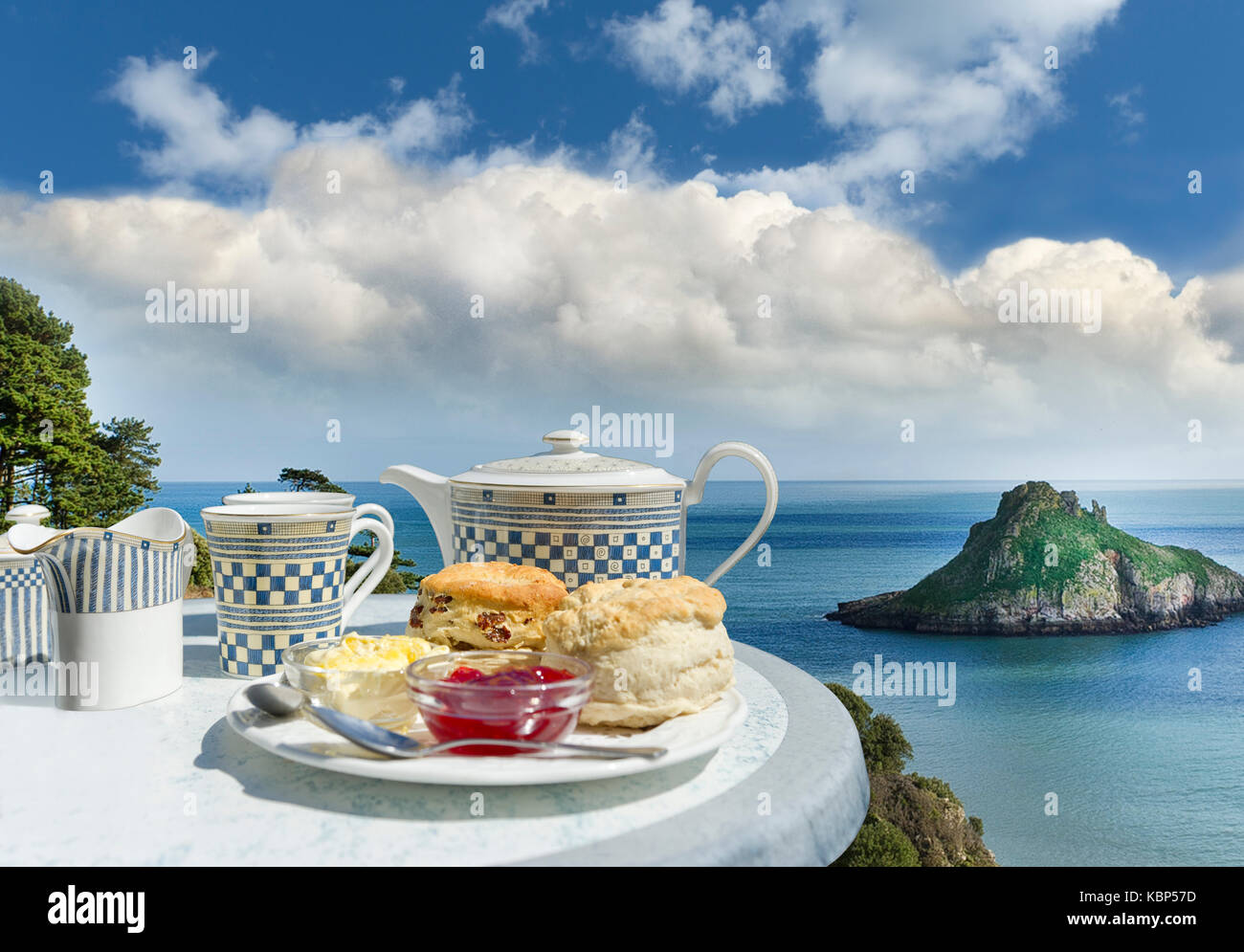 Devon tè alla crema con focaccine e confettura di fragole affacciato sulla vista della Thatcher Rock in Torquay, Devon su una calda e soleggiata giornata estiva. Costa di frutti di mare Foto Stock