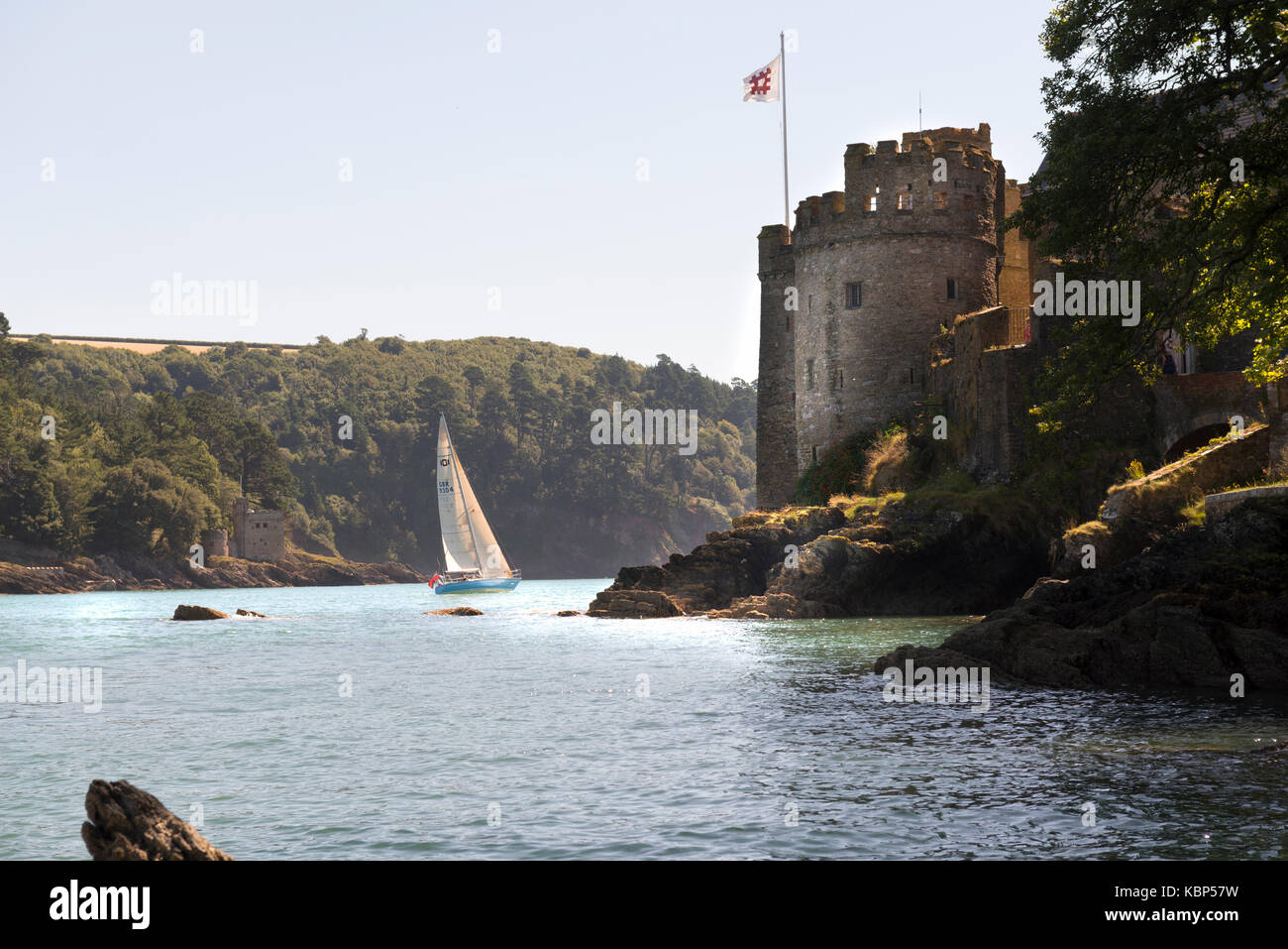 Castello di dartmouth dalle fasi tozza con la tradizione inglese bandiera e uno yacht nella bocca dell'estuario. Foto Stock