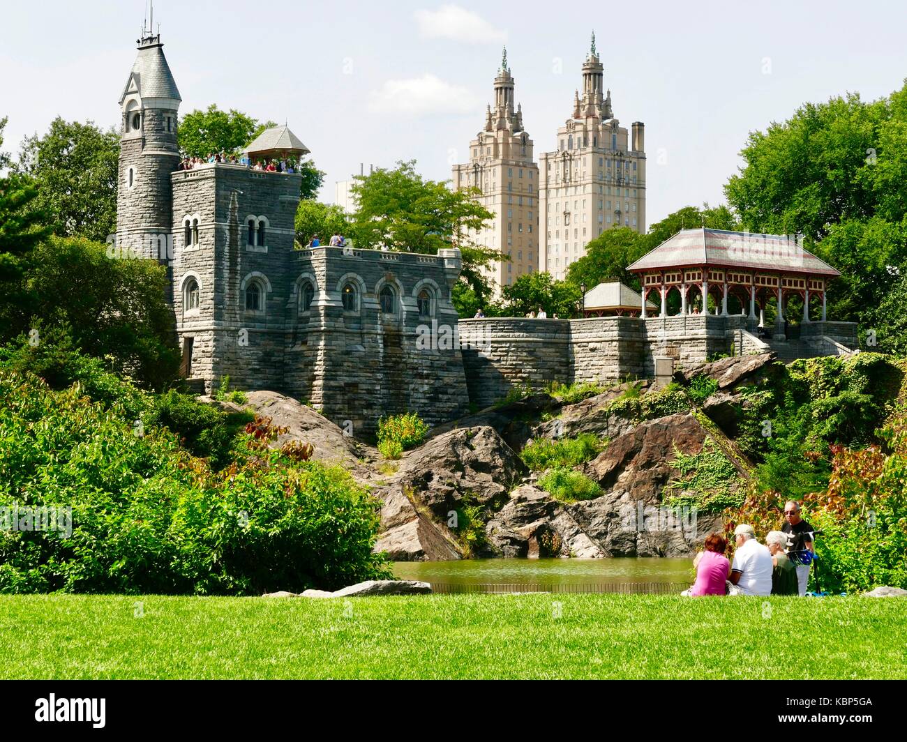 Coppia gli adulti possono rilassarsi a bordo del Central Park lo stagno delle tartarughe, i visitatori si affacciano sul parco dalla sommità del castello Belvedere, tarda estate, New York City, NY, STATI UNITI D'AMERICA. Foto Stock