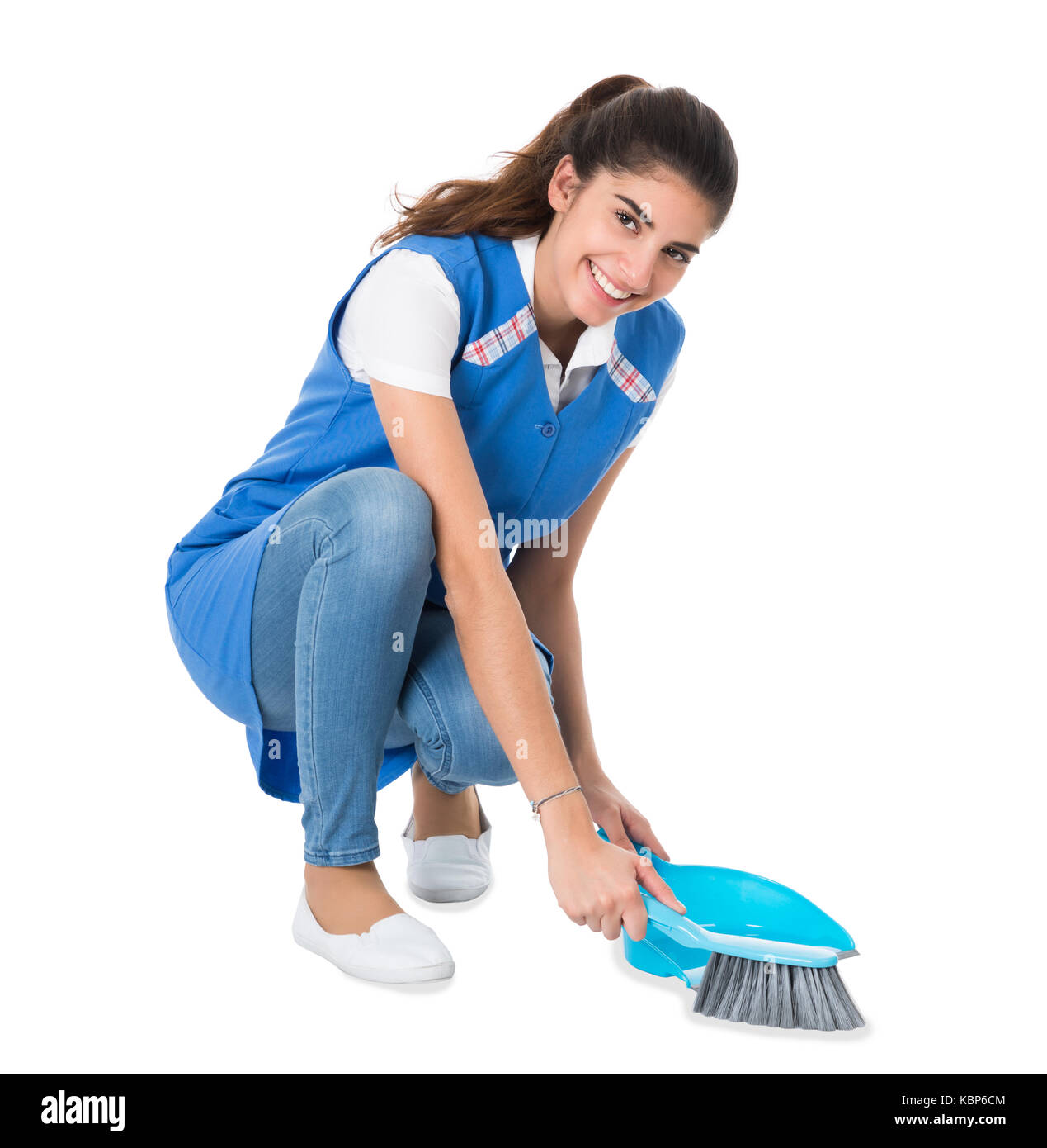 Per tutta la lunghezza della giovane femmina di spazzamento detergente con piccola scopa e paletta su sfondo bianco Foto Stock