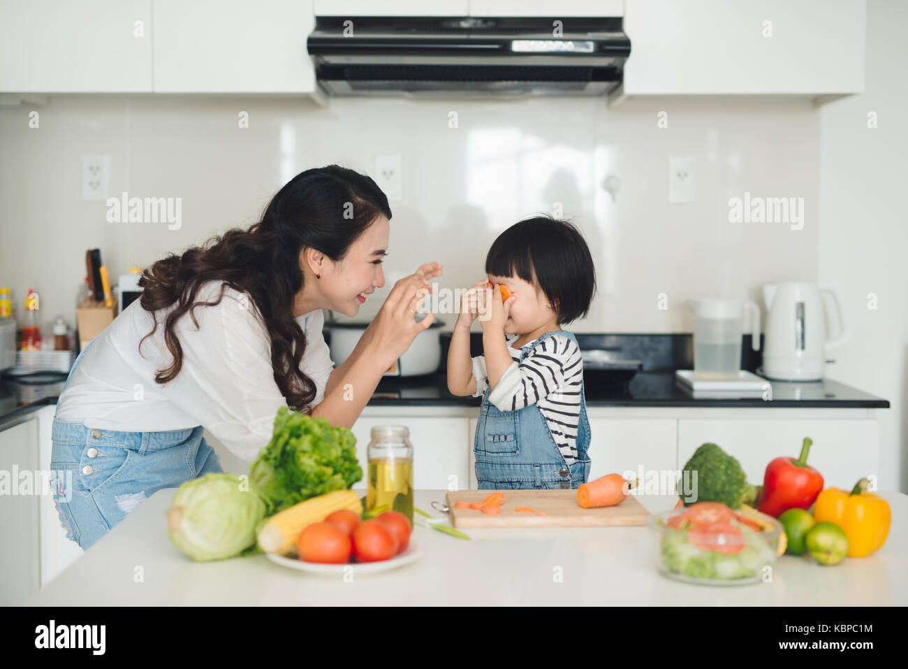 La famiglia felice in cucina. la madre e il bambino figlia sta preparando la frutta e la verdura. Foto Stock