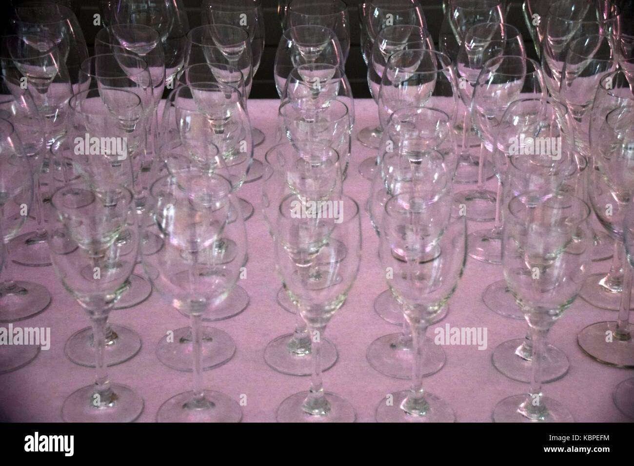 Eleganti calici di vino con riflessi di luce su di essa il tavolo con tovaglia rosa, bicchieri vuoti in una riga Foto Stock