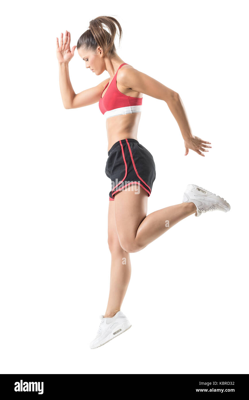 Vista laterale del concentrato di sportività fiducioso donna fitness movimento di salto. corpo pieno lunghezza ritratto isolato su bianco di sfondo per studio. Foto Stock