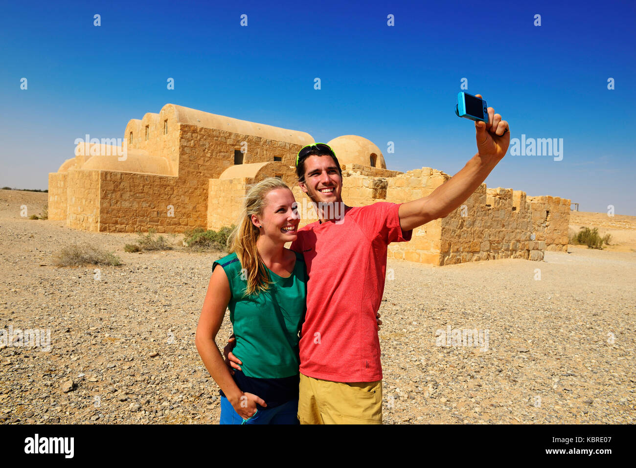 I turisti tenendo selfie, omayyade castello nel deserto, Qasr Amra, Giordania Foto Stock