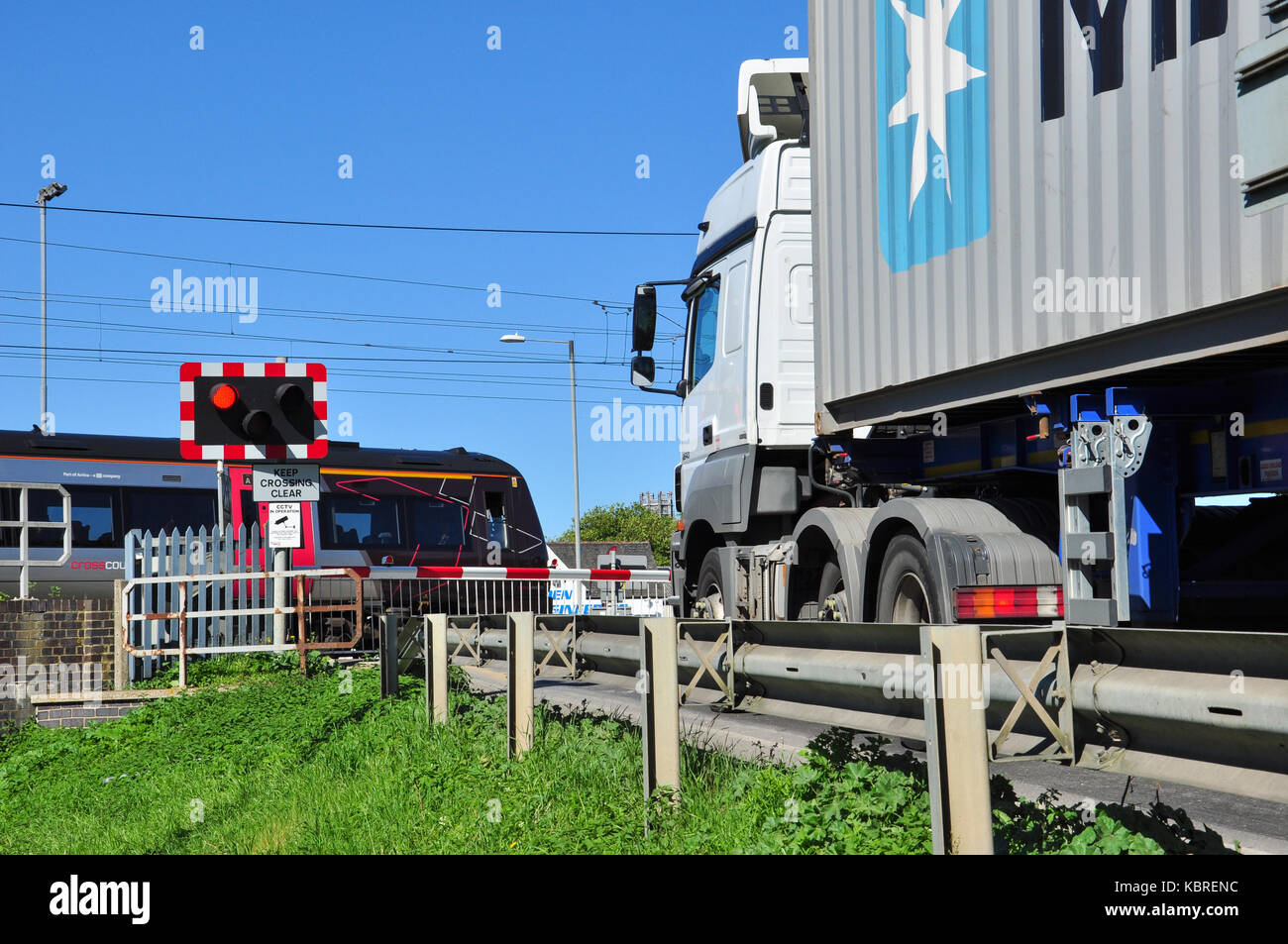 Il passaggio di treni e camion di attesa al passaggio a livello, Ely, Cambridgeshire, Regno Unito Foto Stock