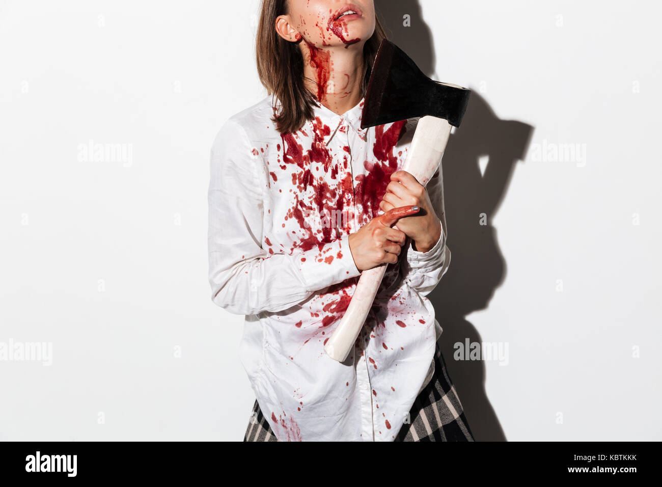 Immagine ritagliata di una donna zombie bleading e ferito il trattenimento di un ax a sua gola isolate su sfondo bianco Foto Stock