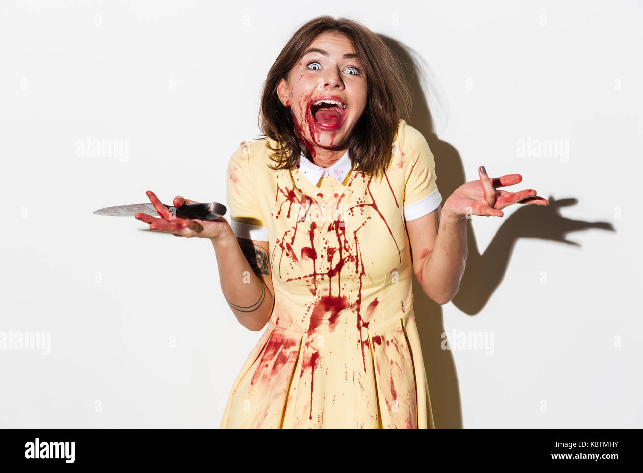 Felice mad zombie donna in possesso di un coltello e ridere isolate su sfondo bianco Foto Stock