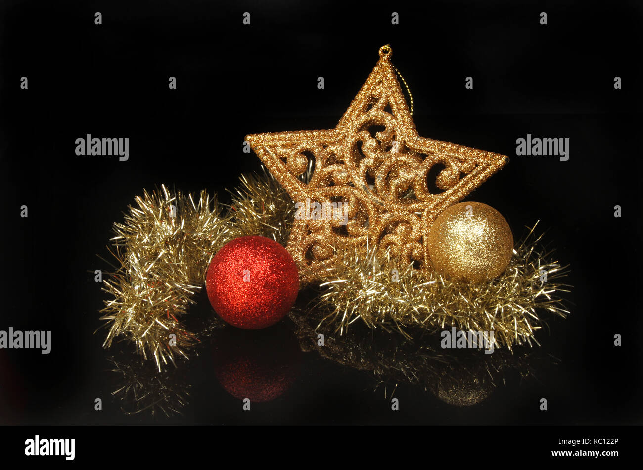 Oro glitter stella di Natale con tinsel e baubles contro uno sfondo nero Foto Stock