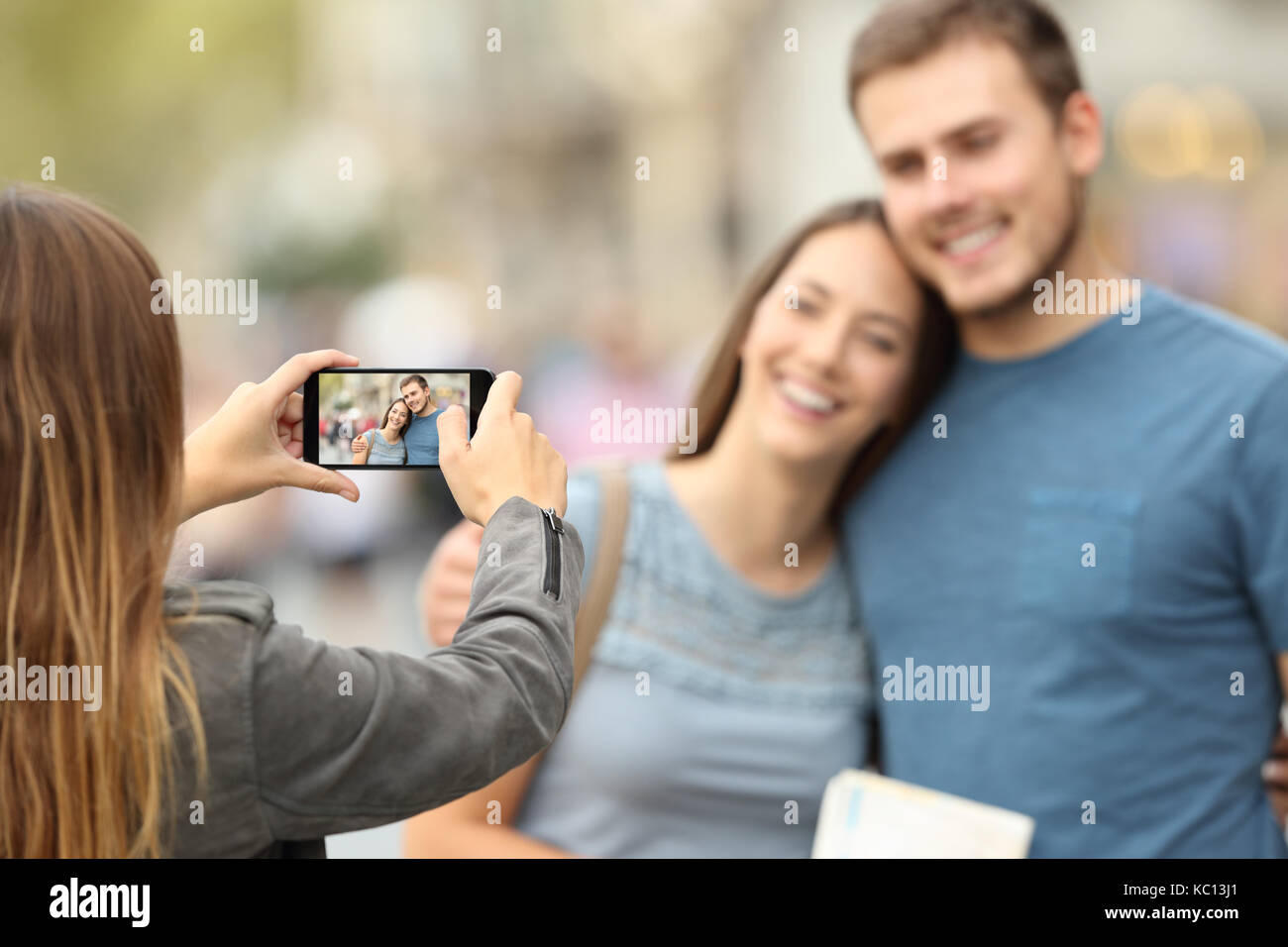 Tre amici felici di scattare le foto con uno smart phone al di fuori sulla strada Foto Stock