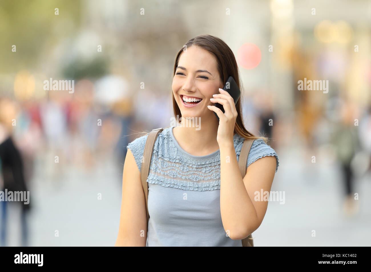 Donna felice chiamata su un telefono mobile a camminare sulla strada Foto Stock