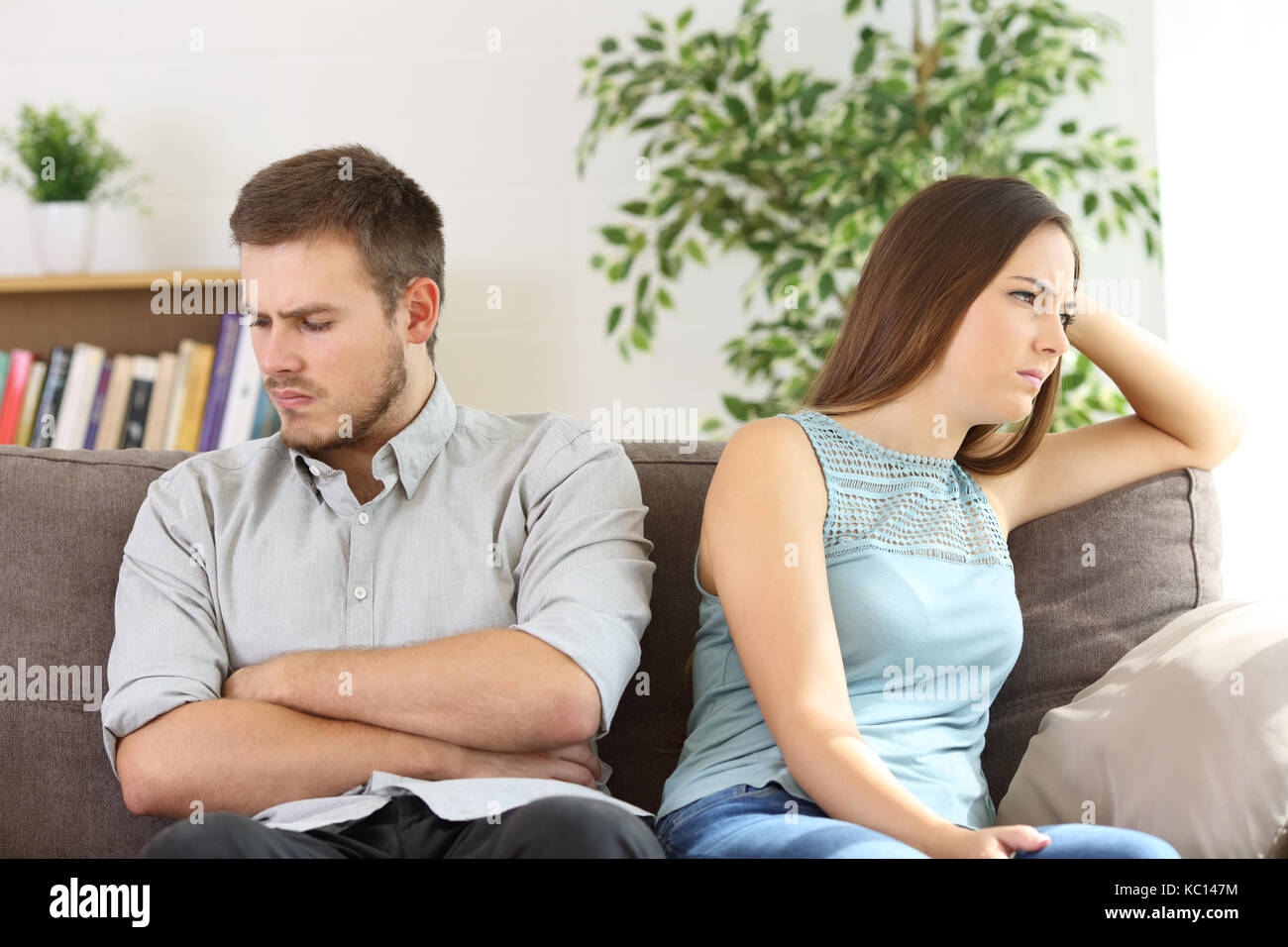 Arrabbiato giovane ignorando ogni altro argomento dopo la seduta su un divano a casa Foto Stock