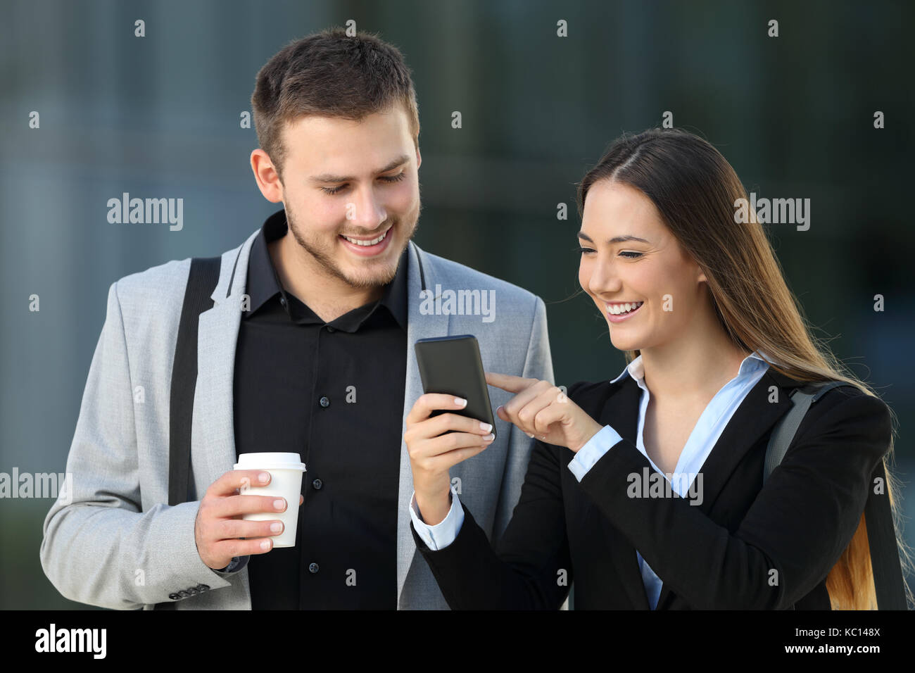 Vista frontale di due dirigenti felici parlando di smart phone contenuto all'esterno permanente sulla strada Foto Stock