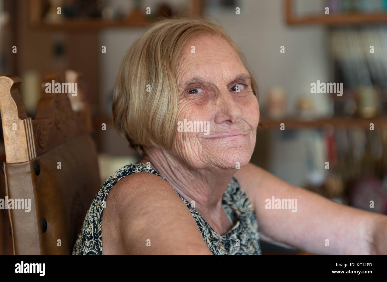 Donna anziana cercando di telecamera a casa, close up Foto Stock